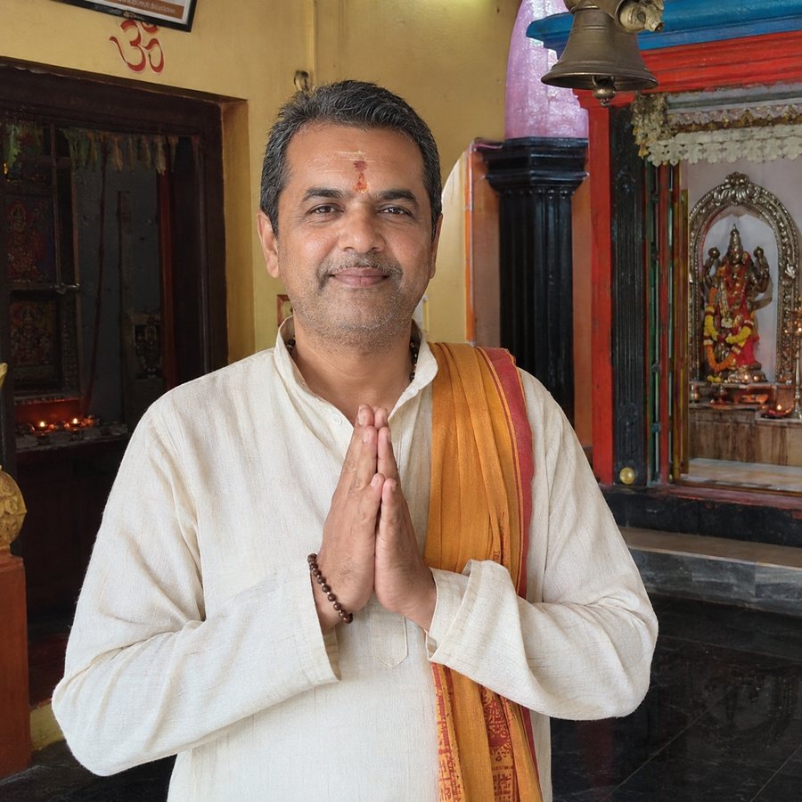 Pandit ji, hands folded, in a temple